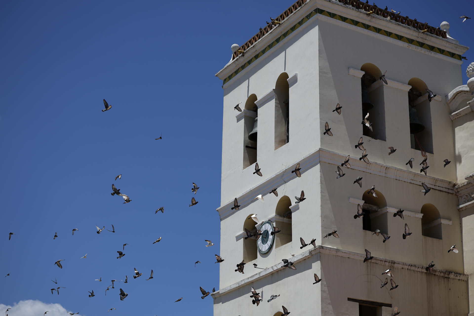 Fotografía del 11 de abril de 2025 de palomas volando frente al reloj de la catedral de la Inmaculada Concepción en Comayagua (Honduras). EFE/ Bienvenido Velasco