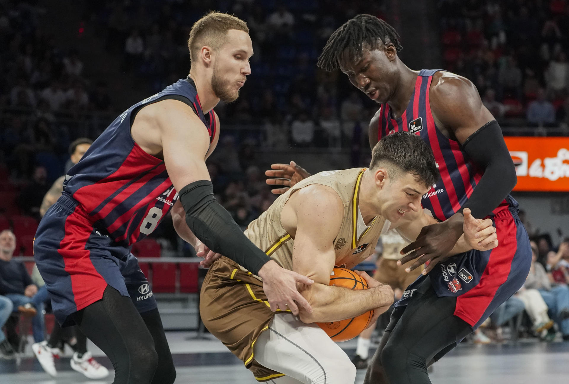 Los jugadores del Baskonia Tadas Sedekerskis y Kalhipa Diop (dcha) pelean por el balón con el jugador del Bàsquet Girona Maxi Fjellerup, durante el partido correspondiente a la fase regular de la Liga Endesa disputado en el Buesa Arena de Vitoria. EFE/L. Rico