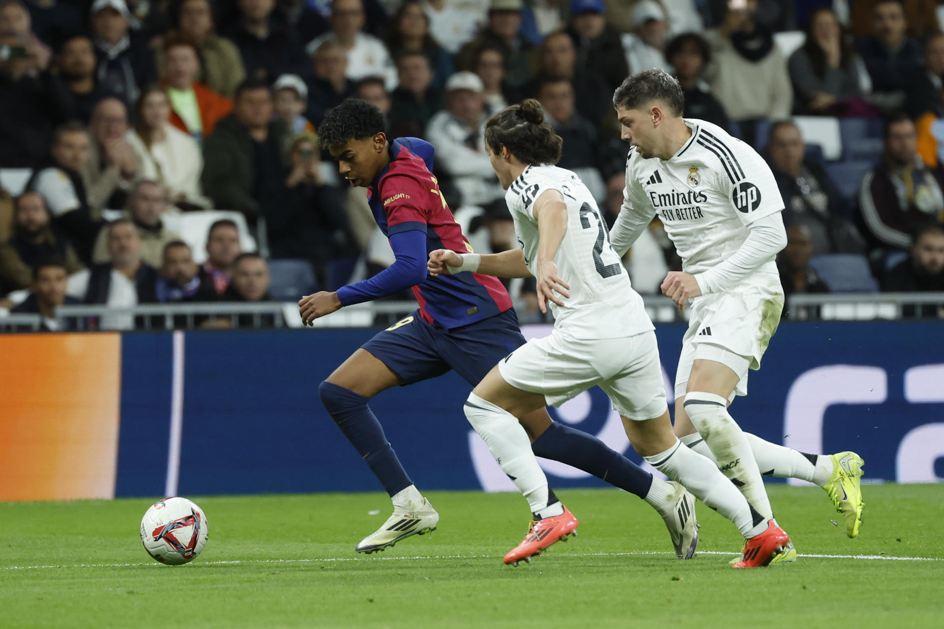 El delantero del FC Barcelona Lamine Yamal (i) se escapa de los madridistas Federico Valverde (d) y Fran García (c) en el partido de la jornada 11 de LaLiga EA Sports. EFE/Juanjo Martín