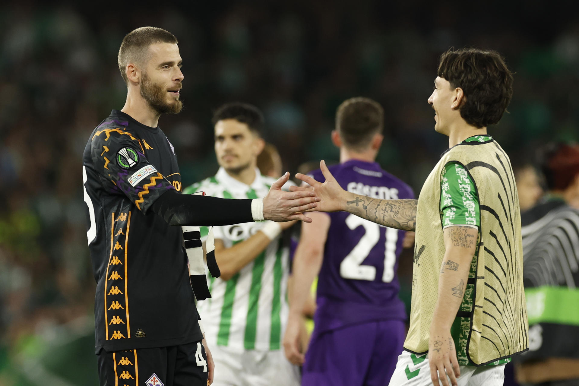 El defensa del Betis Héctor Bellerín (d) saluda al guardameta delFiorentina David De Gea, tras el partido de ida de las semifinales de la Liga Conferencia. EFE/Julio Muñoz