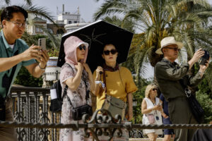 Turistas pasean protegidos con paraguas y pañuelos en la plaza de América de Sevilla, este viernes con temperaturas extremas de hasta 40 grados en Andalucía inusual para el último fin de semana de mayo. EFE /Jose Manuel Vidal