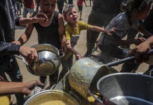 Fotografía de archivo que muestra a niños palestinos que esperan recibir una ración de comida de un comedor social en un campo de refugiados en el norte de la Franja de Gaza. EFE/EPA/MOHAMMED SABER