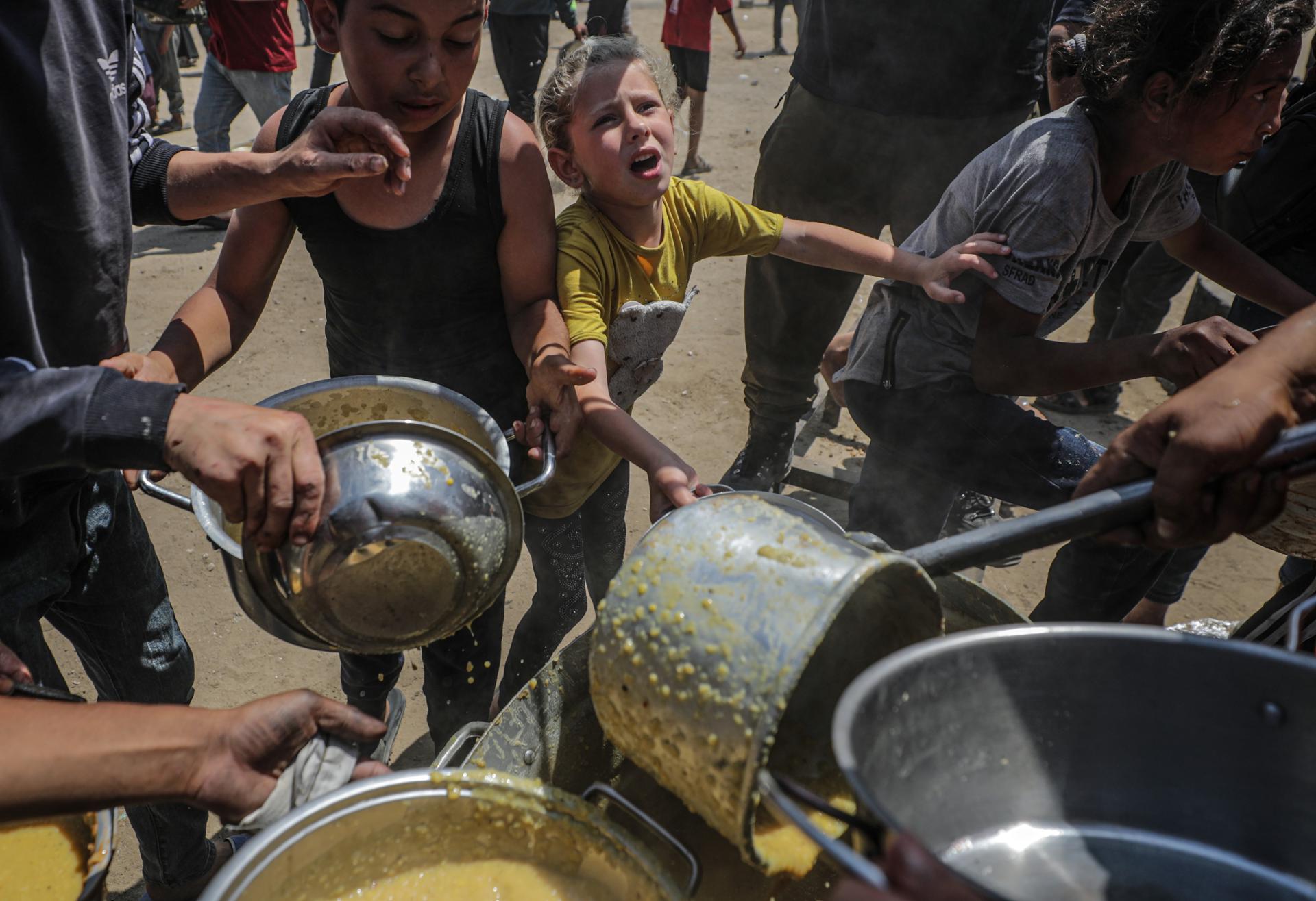 Fotografía de archivo que muestra a niños palestinos que esperan recibir una ración de comida de un comedor social en un campo de refugiados en el norte de la Franja de Gaza. EFE/EPA/MOHAMMED SABER
