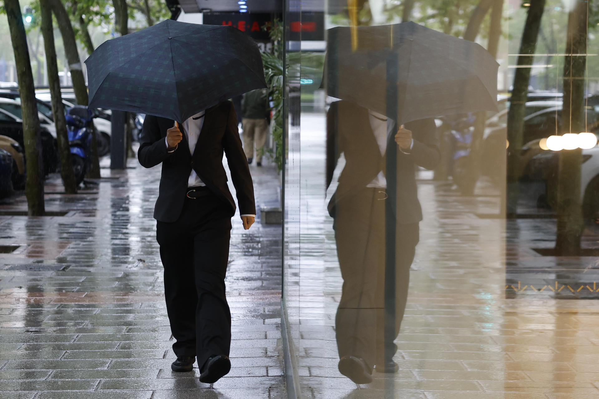 Un hombre se protege de la lluvia caída este lunes en Madrid. EFE/ Mariscal