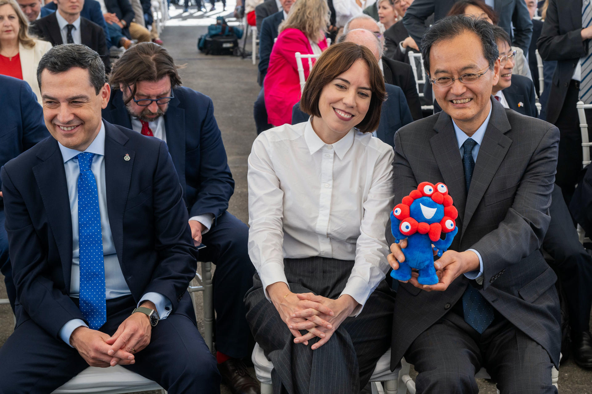 El embajador japonés, Takahiro Nakamae (d) muestra la mascota de la exposición universal de Osaka llamada "Meaku" a la ministra de Ciencia, Innovación y Universidades, Diana Morant en presencia del presidente andaluz, Juanma Moreno, durante la colocación de la primera piedra del acelerador de partículas IFMIF-DONES en Escúzar (Granada). EFE/ Miguel Angel Molina