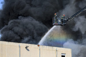Varios medios aéreos y dotaciones terrestres de bomberos trabajan en la extinción de un incendio en una nave industrial de residuos textiles en la localidad castellonense de Almassora, que ha obligado a desalojar el polígono. EFE/Andreu Esteban