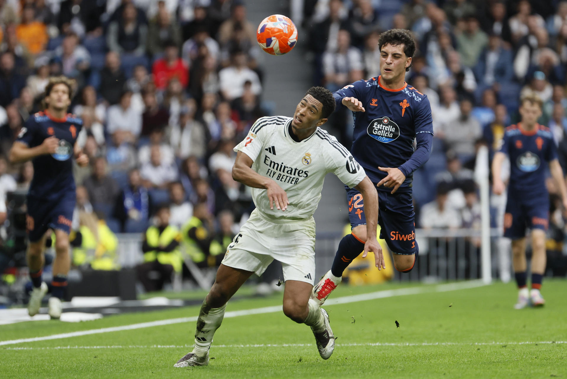 El centrocampista británico del Real Madrid Jude Bellingham (i) lucha por el balón con el delantero del Celta de Vigo Hugo Álvarez durante el partido entre el Real Madrid y el Celta este domingo en el estadio Santiago Bernabéu en Madrid este domingo. EFE/ Ballesteros