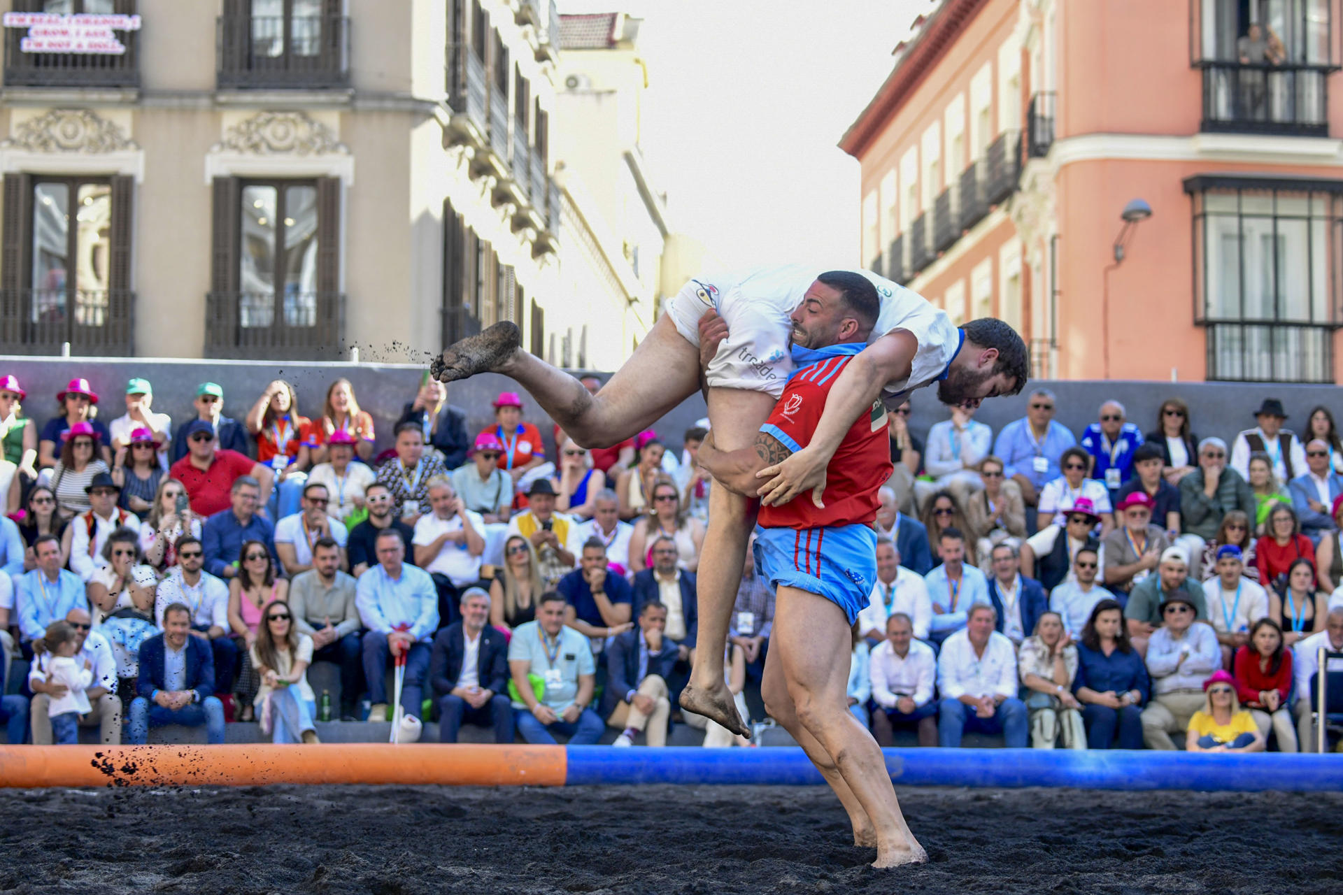 Uno de los combates de la primera competición oficial de lucha canaria que tiene lugar fuera de las islas, una luchada entre los clubes Saladar de Jandía (Fuerteventura) y Candelaria de Mirca (La Palma) sobre un terrero habilitado para la ocasión en la plaza de Callao de Madrid con ceniza del volcán Tajogaite. EFE/ Victor Lerena