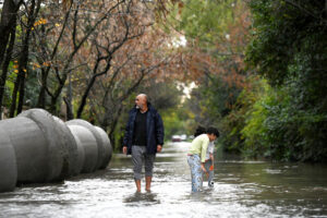Personas caminan por una vía inundada este sábado, en el barrio La Bota (Argentina). EFE/ STR