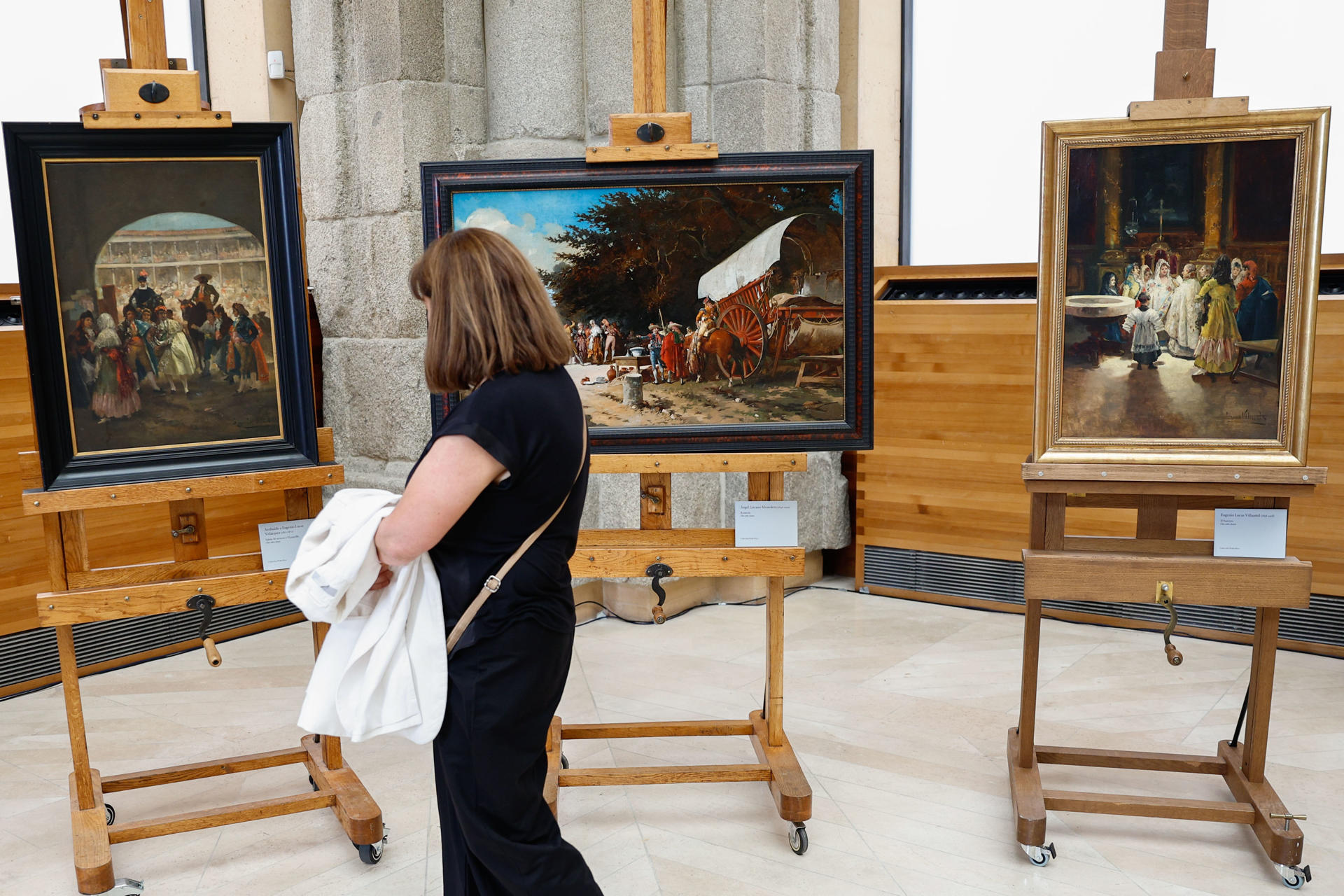 Una persona contemplan algunos cuadros durante el acto presidido por el ministro de Cultura, Ernest Urtasun, en el que se han restituido varias obras incautadas durante la guerra civil y no devueltas por el franquismo, este jueves en el Museo del Prado de Madrid. EFE/ Rodrigo Jiménez