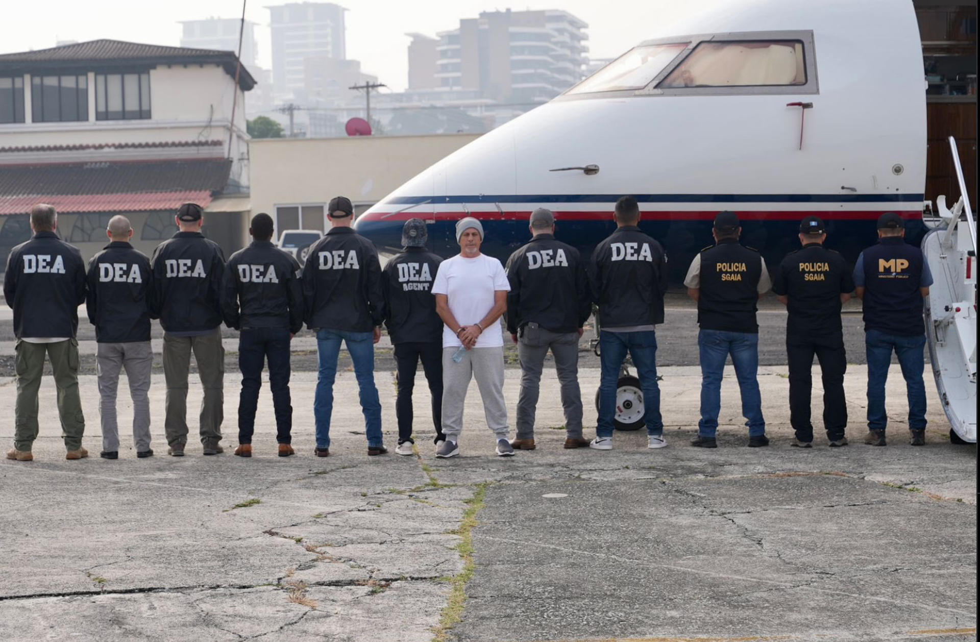 Fotografía cedida por la Embajada de los Estados Unidos en Guatemala que muestra a integrantes de las autoridades guatemaltecas y agentes del Departamento Antidrogas de Estados Unidos, custodiando al supuesto líder del cartel del narcotráfico 'Los Huistas',  Aler Baldomero Samayoa (c) este viernes en Ciudad de Guatemala (Guatemala). EFE/Embajada de los Estados Unidos en Guatemala