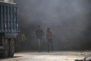Palestinos corren para cubrirse mientras se eleva el humo tras un ataque aéreo israelí al oeste de la ciudad de Gaza, en la Franja de Gaza. EFE/MOHAMMED SABER