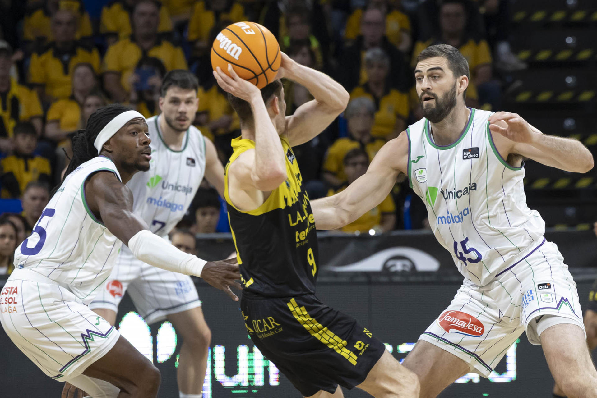 El base de La Laguna Tenerife Marcelinho Huertas (c) y los jugadores del Unicaja Málaga Kendrick Perry (i), y David Kravish (d) durante el partido de la jornada 31 de la Liga Endesa que enfrentó a ambos equipos este jueves en el pabellón Santiago Martín en La Laguna (Tenerife). EFE/ Miguel Barreto