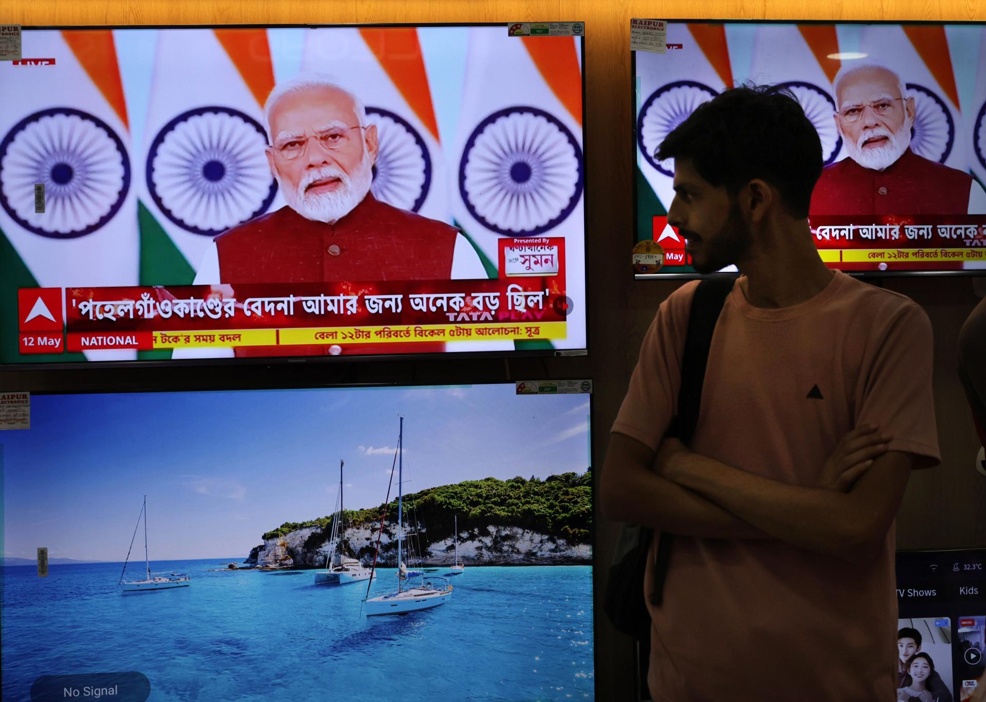 Una persona se para frente a pantallas de televisión que muestran una transmisión en vivo del primer ministro indio, Narendra Modi, dirigiéndose a la nación por primera vez desde las recientes escaladas en el conflicto entre India y Pakistán, en una tienda de electrónica en Kolkata, India oriental, 12 de mayo de 2025. Un alto el fuego entre Pakistán e India entró en vigor el 10 de mayo de 2025, después de días de escalada militar. EFE/EPA/PIYAL ADHIKARY