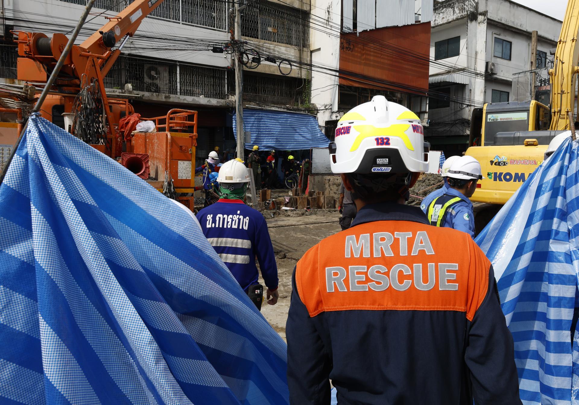 Rescatistas y obreros participan en una operación para rescatar a un trabajador que cayó en un socavón de 19 metros de profundidad en una obra de metro en Bangkok. EFE/EPA/NARONG SANGNAK