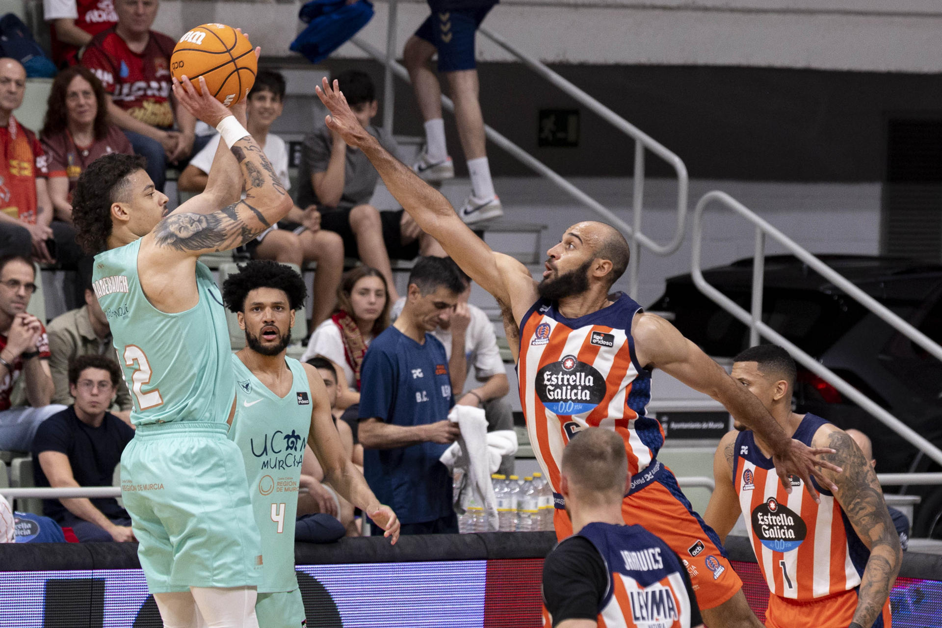 El base estadounidense de UCAM Murcia Jonah Radebaugh (i), lanza a canasta ante la presión del escolta del Reino Unido de Leyma Coruña Phil Scrubb (d), durante el partido de la trigésimo tercera jornada de la liga Endesa en el Palacio de los Deportes de Murcia. EFE/Marcial Guillén
