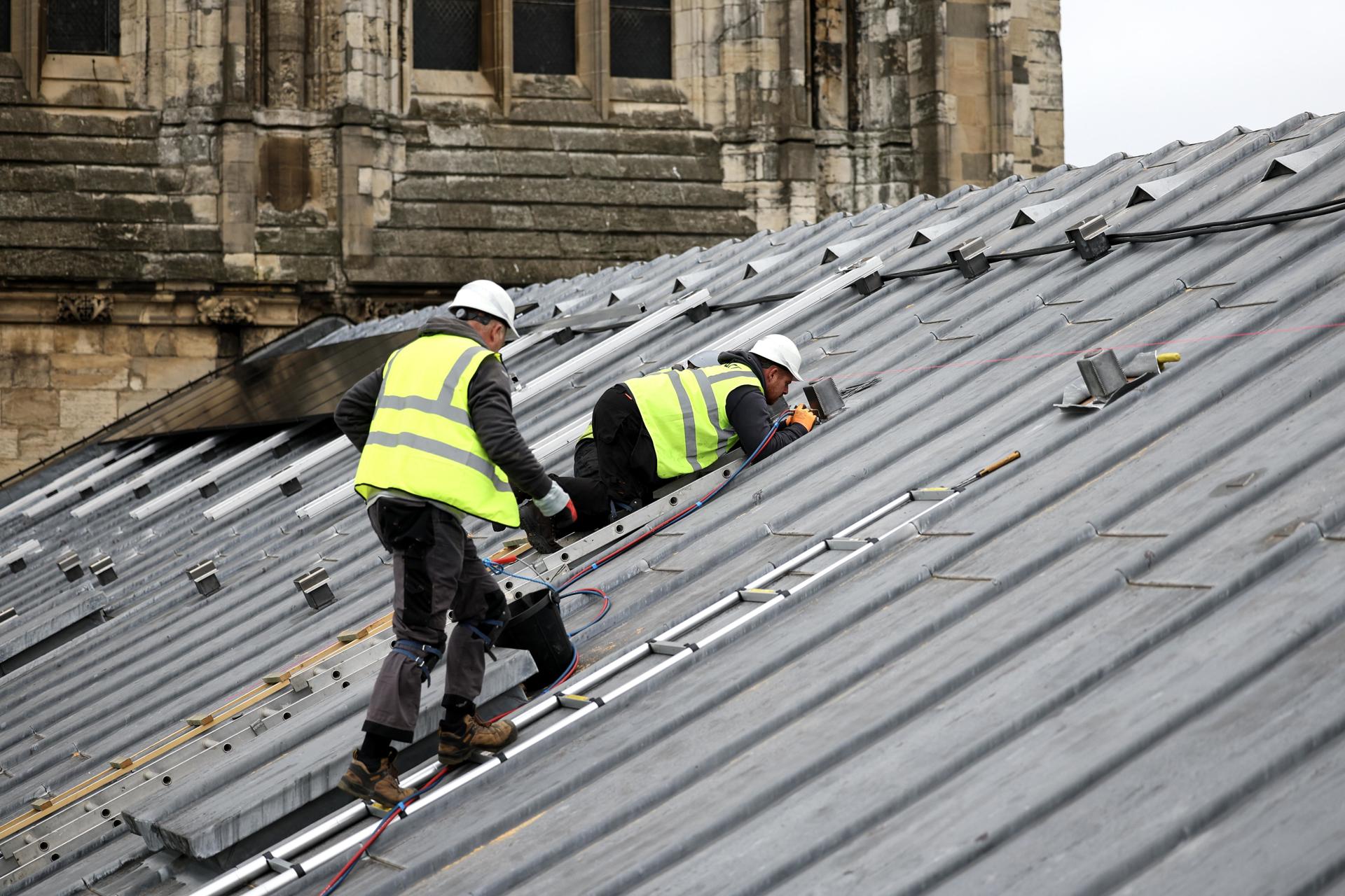 Imagen de archivo de unos trabajadores colocando paneles solares en un edificio. EFE/EPA/ADAM VAUGHAN
//////////
York (Reino Unido), 31/10/2024.- Los miembros del equipo trabajan mientras se instalan 184 paneles solares en el tejado de la Quire Sur de la catedral de York Minster en York, Gran Bretaña, 31 de octubre de 2024. Los paneles se están instalando como parte de un esfuerzo por reducir la huella de carbono de la diócesis de la catedral, una de las más grandes del mundo. Se espera que los paneles generen hasta 70,000 kWh de energía anualmente, aproximadamente un tercio del consumo total de energía de la catedral, y podrían reducir las emisiones anuales de CO2 en alrededor de 13 toneladas, según la catedral de York Minster. (United Kingdom) EFE/EPA/ADAM VAUGHAN