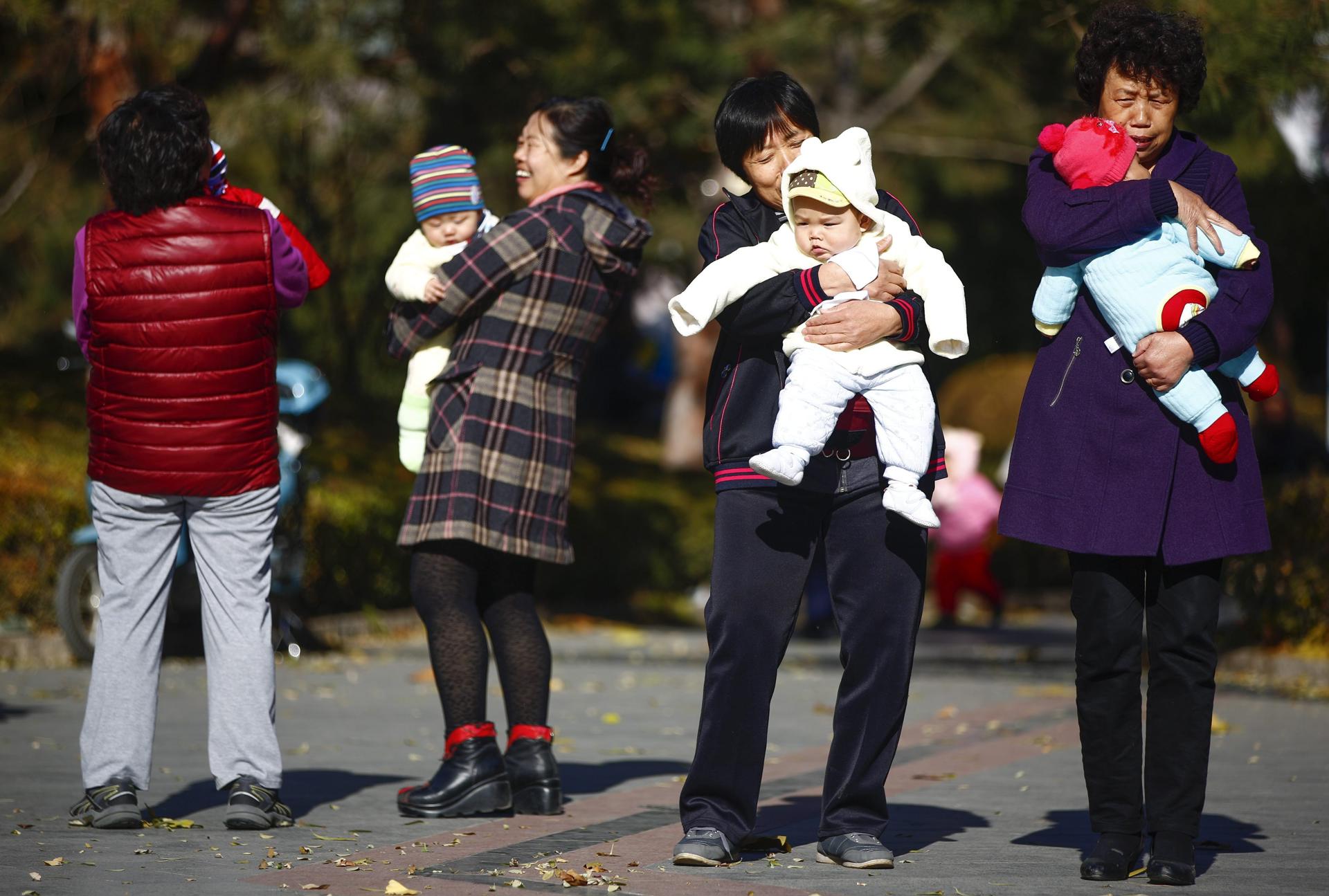 Fotografía de archivo que muestra a mujeres que sujetan en brazos a bebés en un parque de Pekín, China. EFE/Diego Azubel