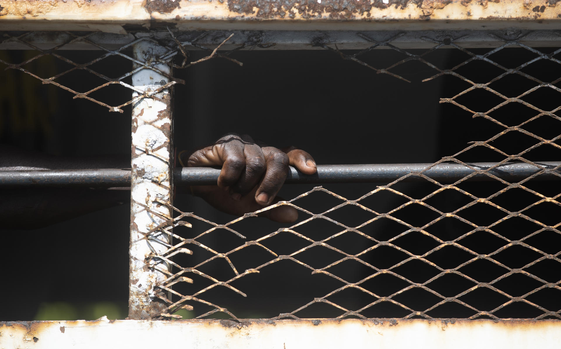 Fotografía de archivo en donde se ve la mano de un migrante tras una reja. EFE/ Orlando Barría