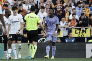 El delantero del Real Madrid Vinicius jr. se dirige al árbitro Ricardo de Burgos Bengoechea, tras recibir insultos racistas de unos aficionados del Valencia, durante el partido que enfrentó a ambos conjuntos el 21 de mayo de 2023. EFE/ Biel Alino