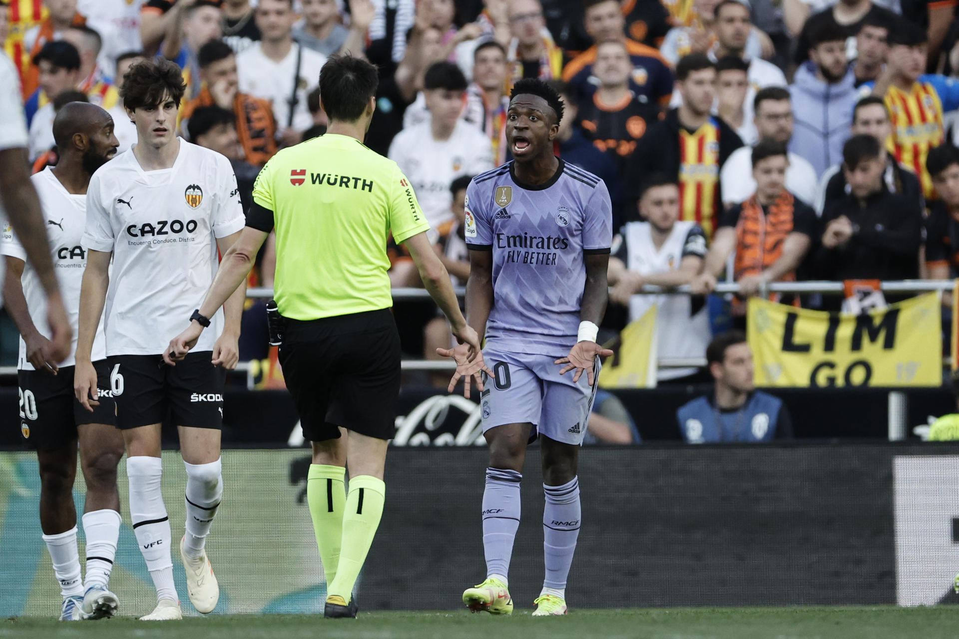 El delantero del Real Madrid Vinicius jr. se dirige al árbitro Ricardo de Burgos Bengoechea, tras recibir insultos racistas de unos aficionados del Valencia, durante el partido que enfrentó a ambos conjuntos el 21 de mayo de 2023. EFE/ Biel Alino