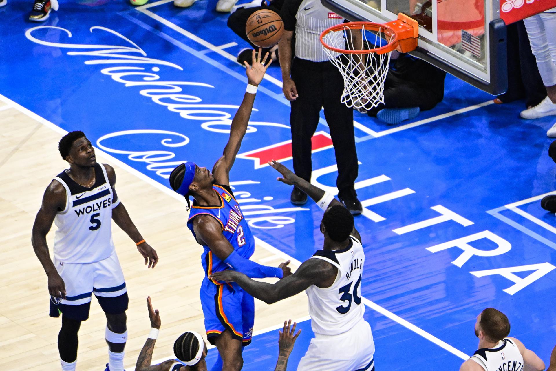 El escolta de los Thunder, Shai Gilgeous-Alexander (c-i), lanza a canasta ante la marca del alero de los Minnesota Timberwolves, Julius Randle (c-d) durante el quinto juego de las finales de la Conferencia Oeste, que han dominado este miércoles por 124-94 y cuya serie han ganado por 4-1, saldo que los clasifica para las Finales de la NBA, que comenzarán el 5 de junio. EFE/EPA/GERALD LEONG