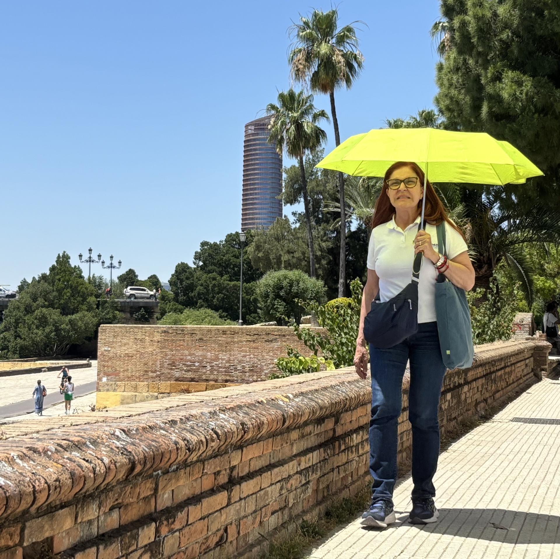 Una mujer camina por una calle de Sevilla mientras se cubre del sol con una sombrilla, este miércoles con alta temperaturas. EFE/Carlos Rivera