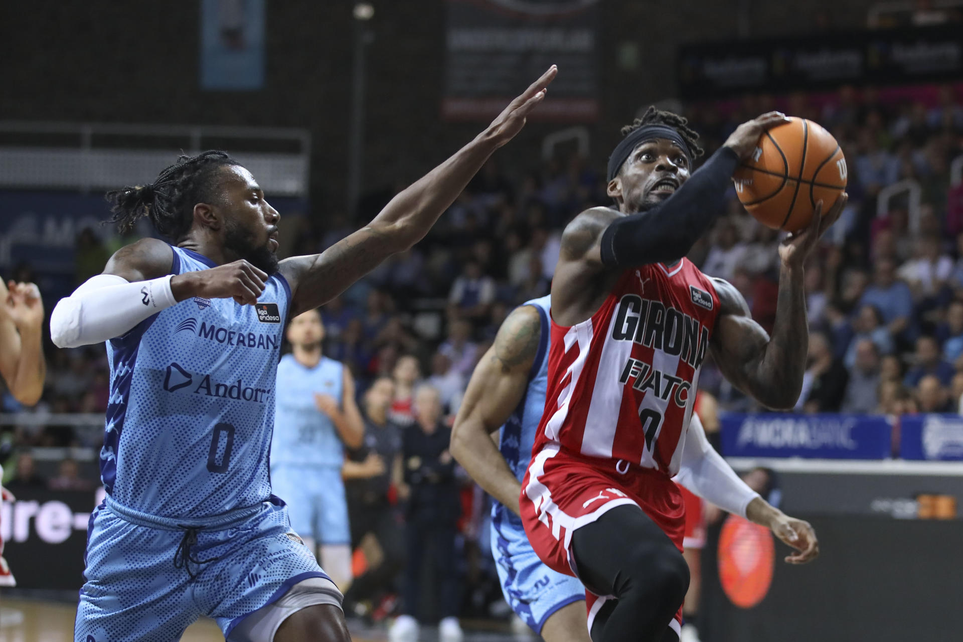 El base nigeriano de Basquet Girona, Ike Iroegbu (d), entra a canasta ante el base estadounidense de Morabanc Andorra, Shannon Evans, durante el partido correspondiente a la trigésimo primera jornada de la Liga Endesa disputado este sábado en el Polideportivo Toni Martí. EFE / Fernando Galindo.
