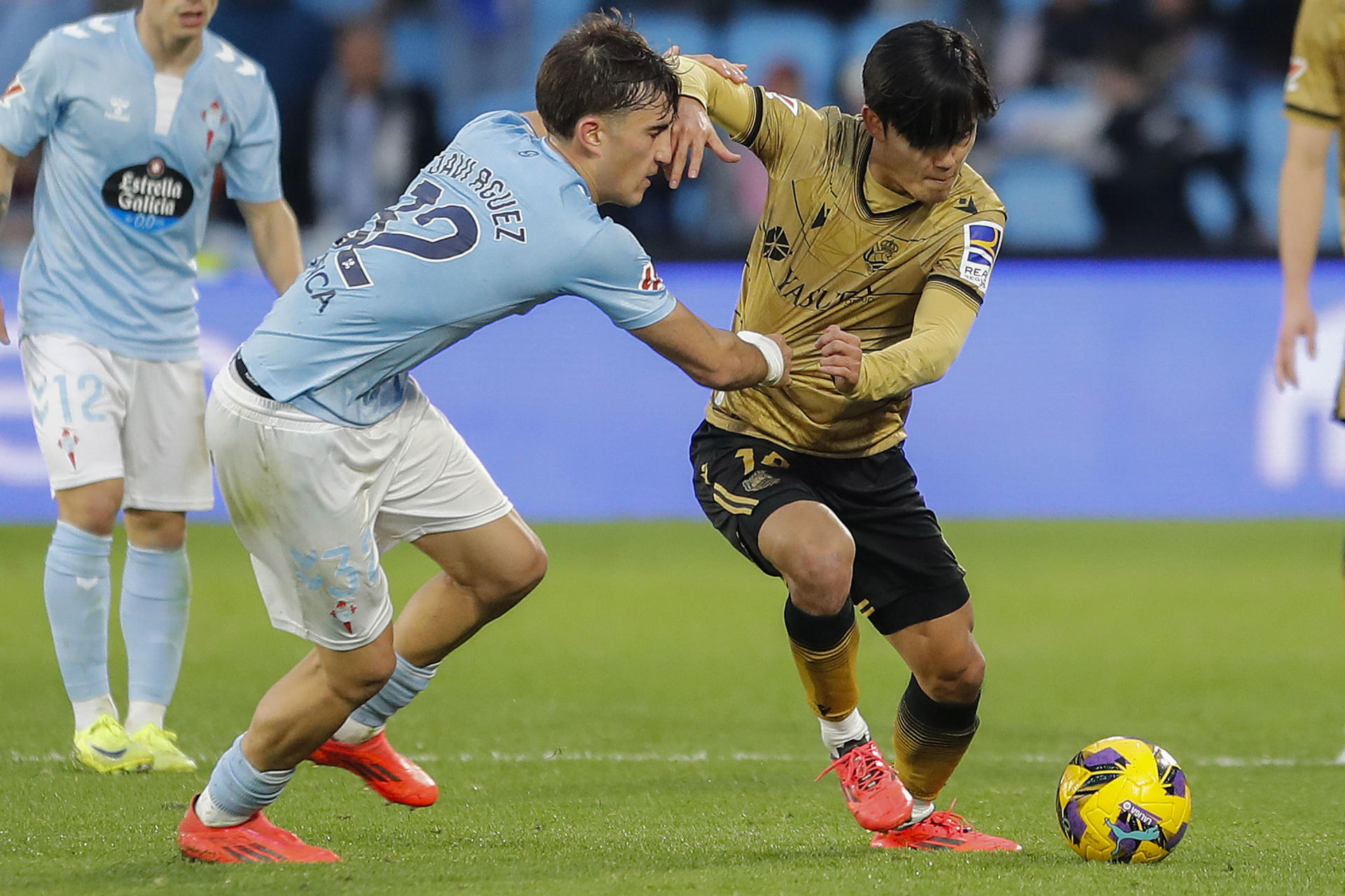 El defensa del Celta de Vigo Javi Rodríguez (i) pugna por un balón con el centrocampista japonés de la Real Sociedad Take Kubo en el partido de Liga celebrado en el estadio Balaídos de Vigo. EFE / Salvador Sas