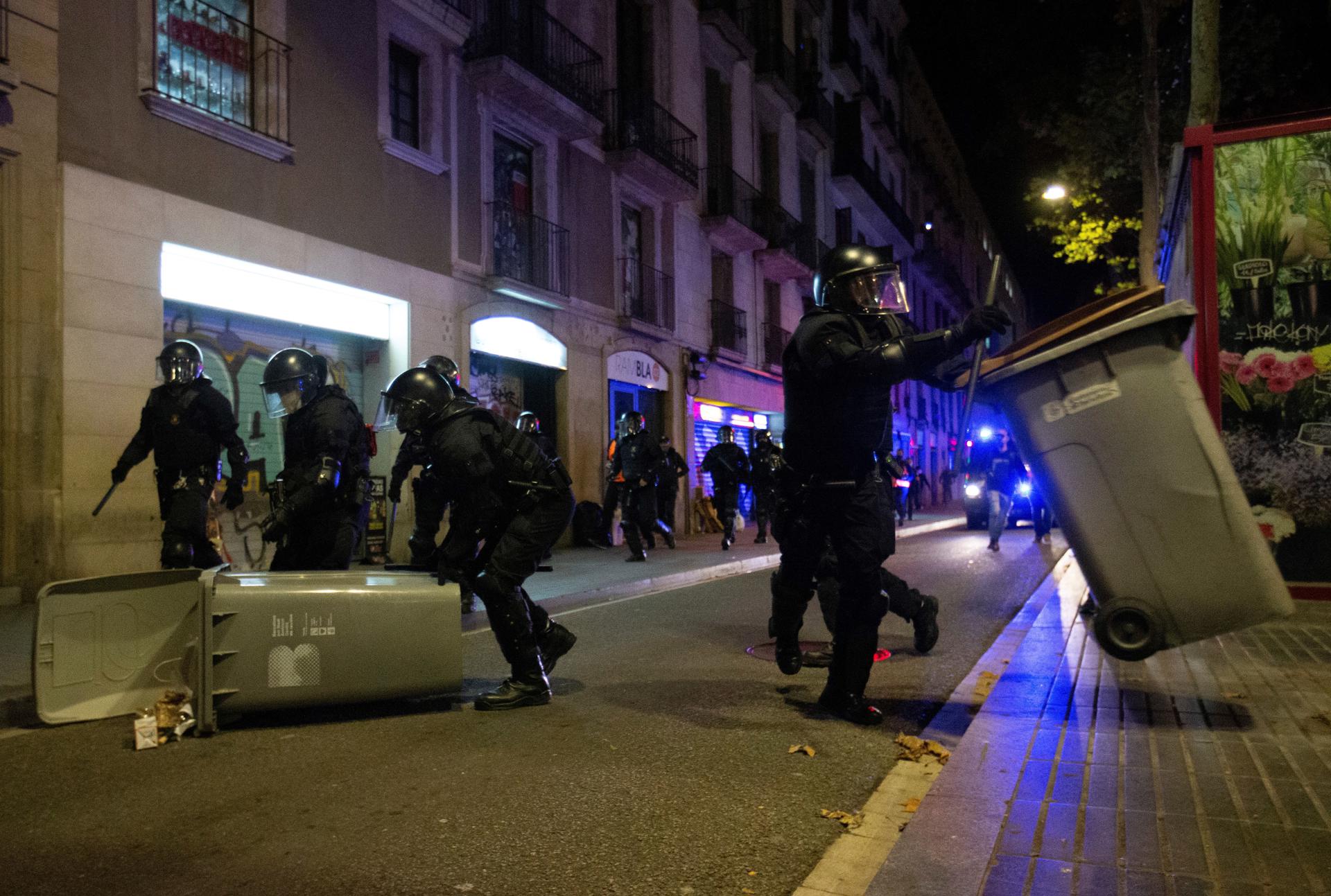 Miembros de los Mozos de Escuadra retiran cubos de basura en los disturbios producidos en Barcelona a raíz del proces. EFE / Enric Fontcuberta.