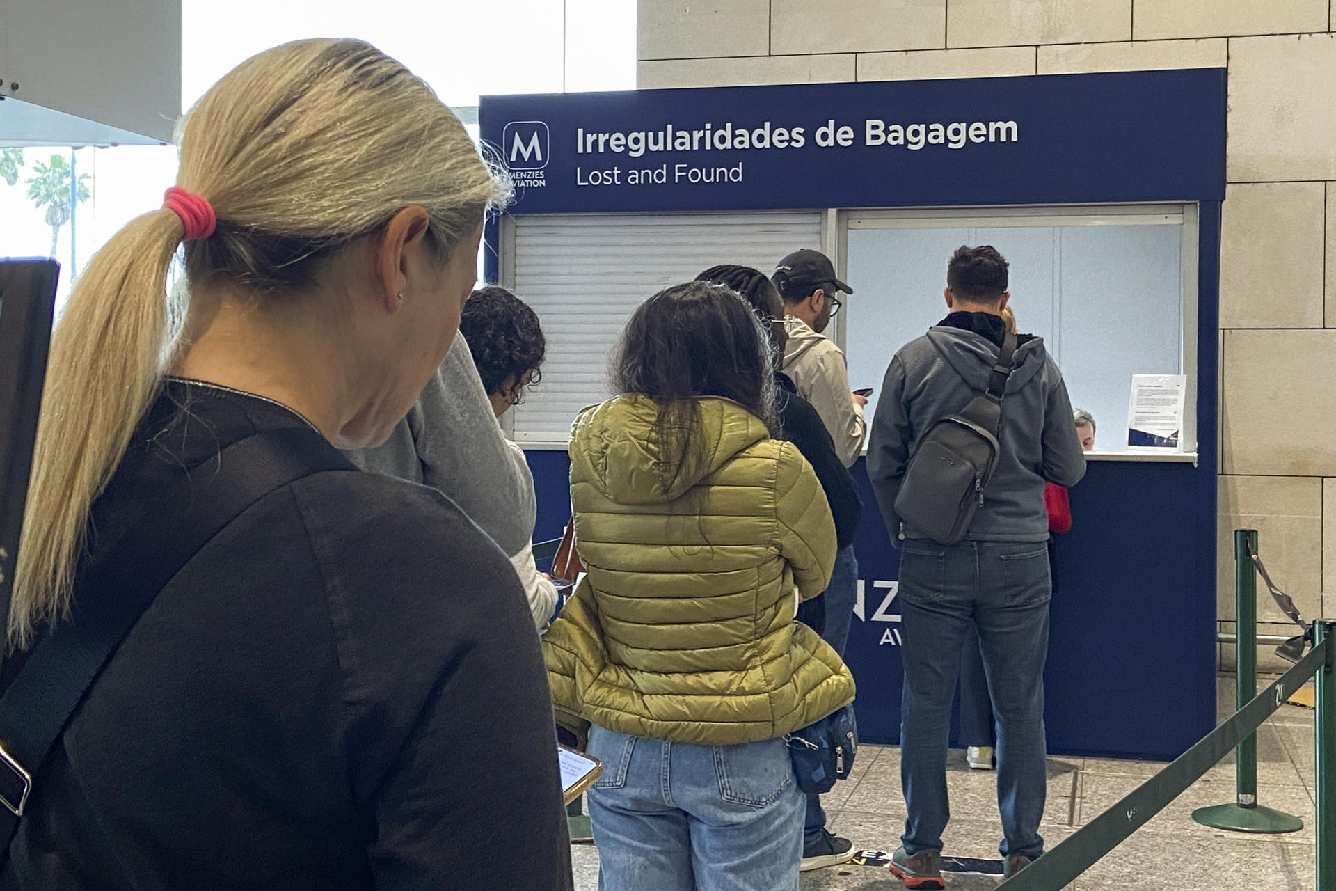 Varias personas esperan este viernes a ser atendidas en el mostrador de incidencias con el equipaje del aeropuerto Humberto Delgado de Lisboa, donde aún hay viajeros que dicen no saber dónde están maletas que trajeron consigo este lunes, cuando un apagón dejó a oscuras la península ibérica. EFE/ Carlos Caselles