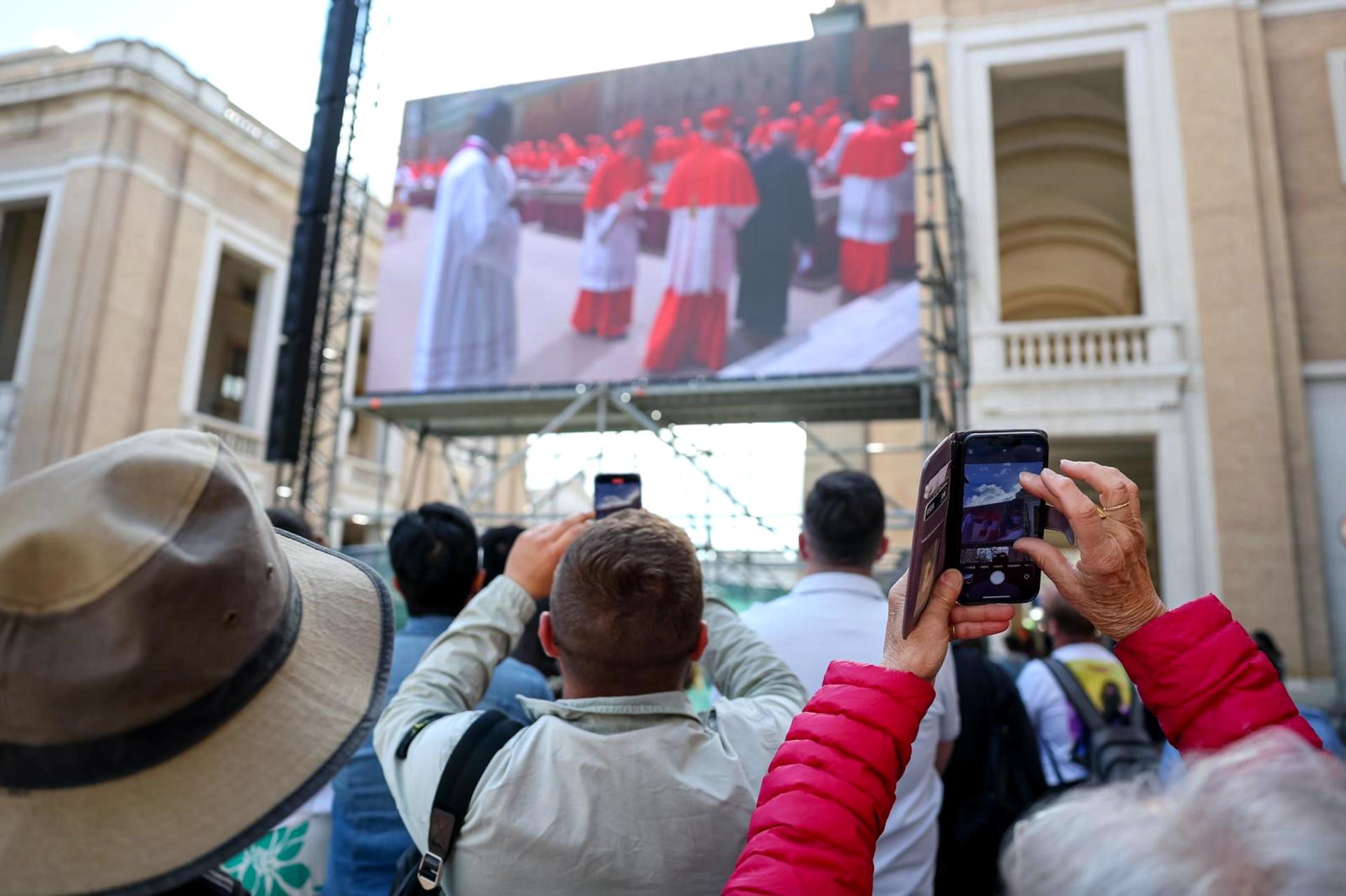 Fieles observan una pantalla gigante que muestra imágenes de los cardenales electores cuando comienza el cónclave para elegir un nuevo papa, en una calle que conduce a la Plaza de San Pedro en Roma, Italia, 07 de mayo de 2025. (Papa, Cardenal, Italia, Roma) EFE/EPA/ANDREA SOLERO
```