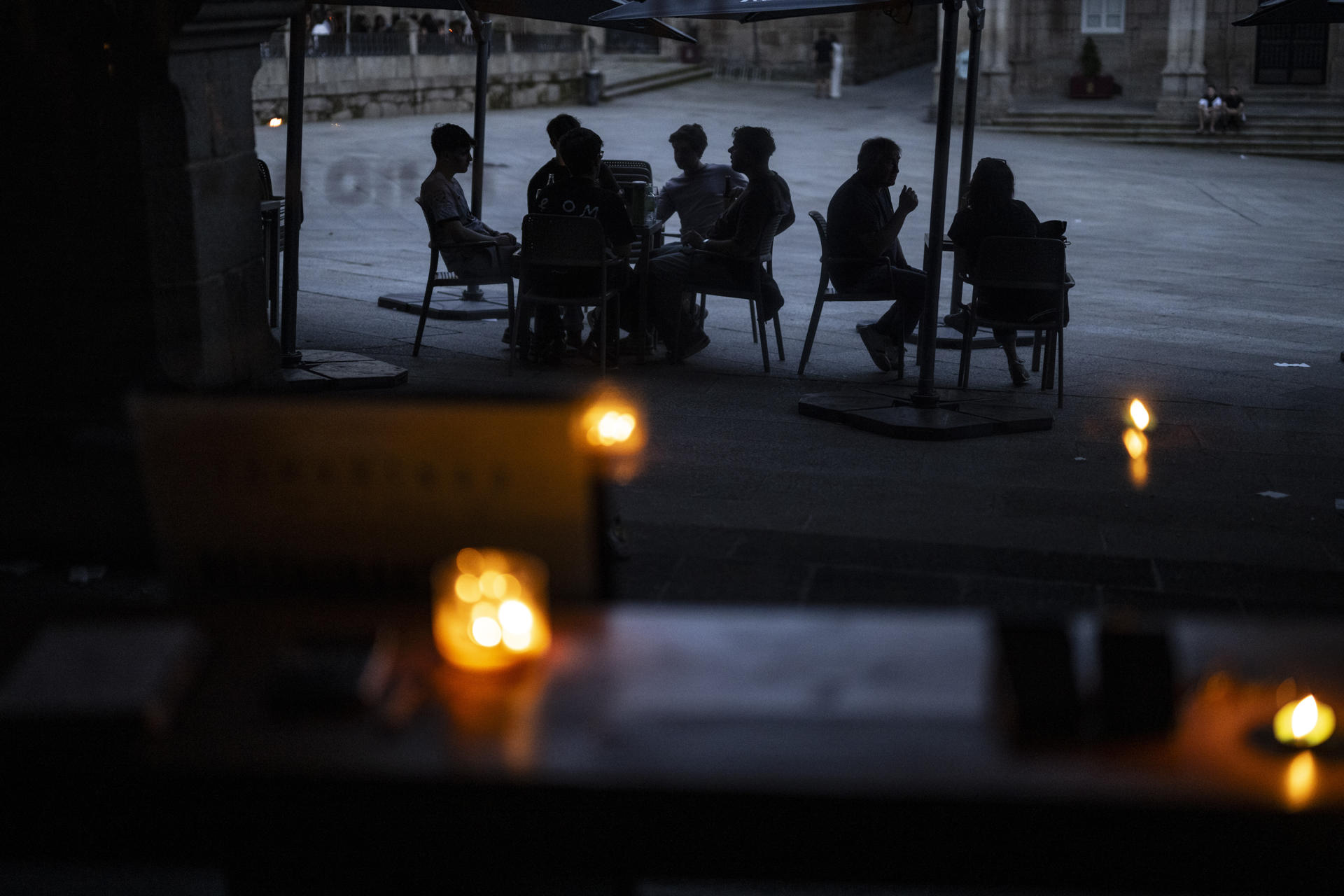 Imagen de archivo de varias personas en la terraza de un bar al caer la noche durante el apagón eléctrico en Ourense. EFE/ Brais Lorenzo