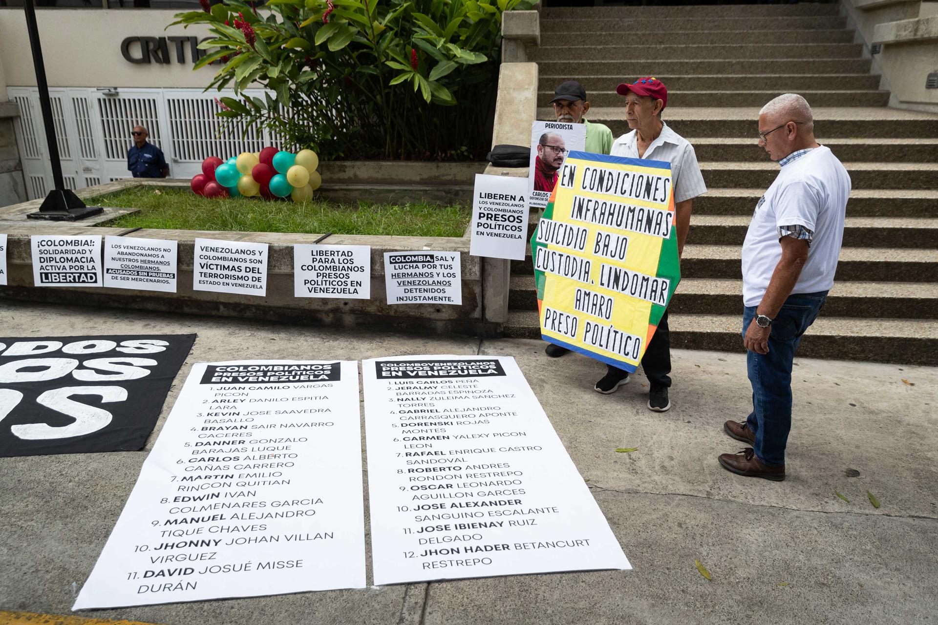 Personas sostienen carteles en una manifestación por la liberación de los "presos políticos" frente a la Embajada de Colombia, este lunes en Caracas (Venezuela). EFE/ Ronald Peña R