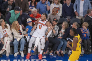 Jalen Brunson (c), de Knicks, cae sobre algunos aficionados este jueves durante un partido de la NBA ante los Indiana Pacers en el Madison Square Garden en Nueva York. EFE/ Ángel Colmenares