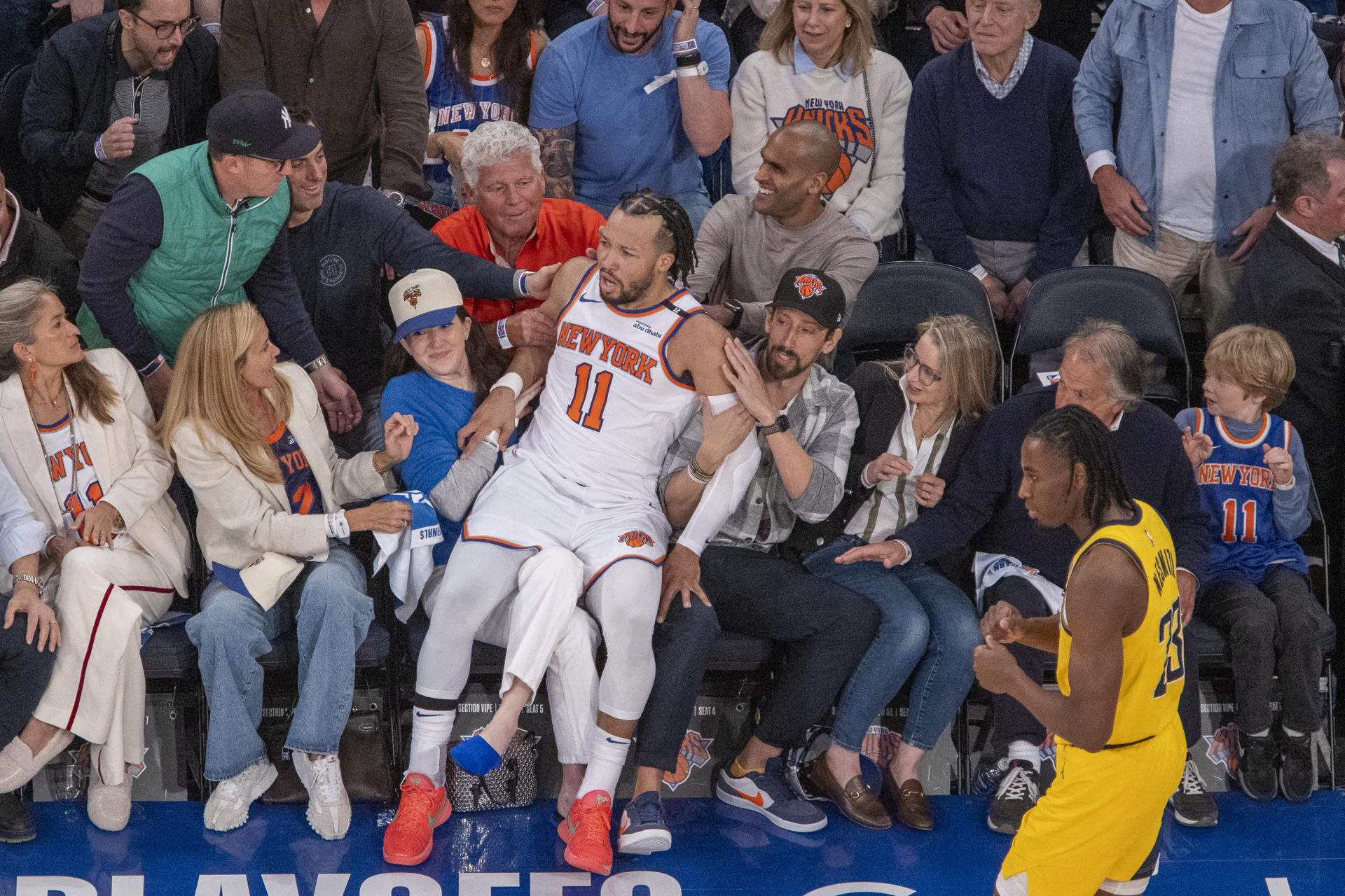 Jalen Brunson (c), de Knicks, cae sobre algunos aficionados este jueves durante un partido de la NBA ante los Indiana Pacers en el Madison Square Garden en Nueva York. EFE/ Ángel Colmenares