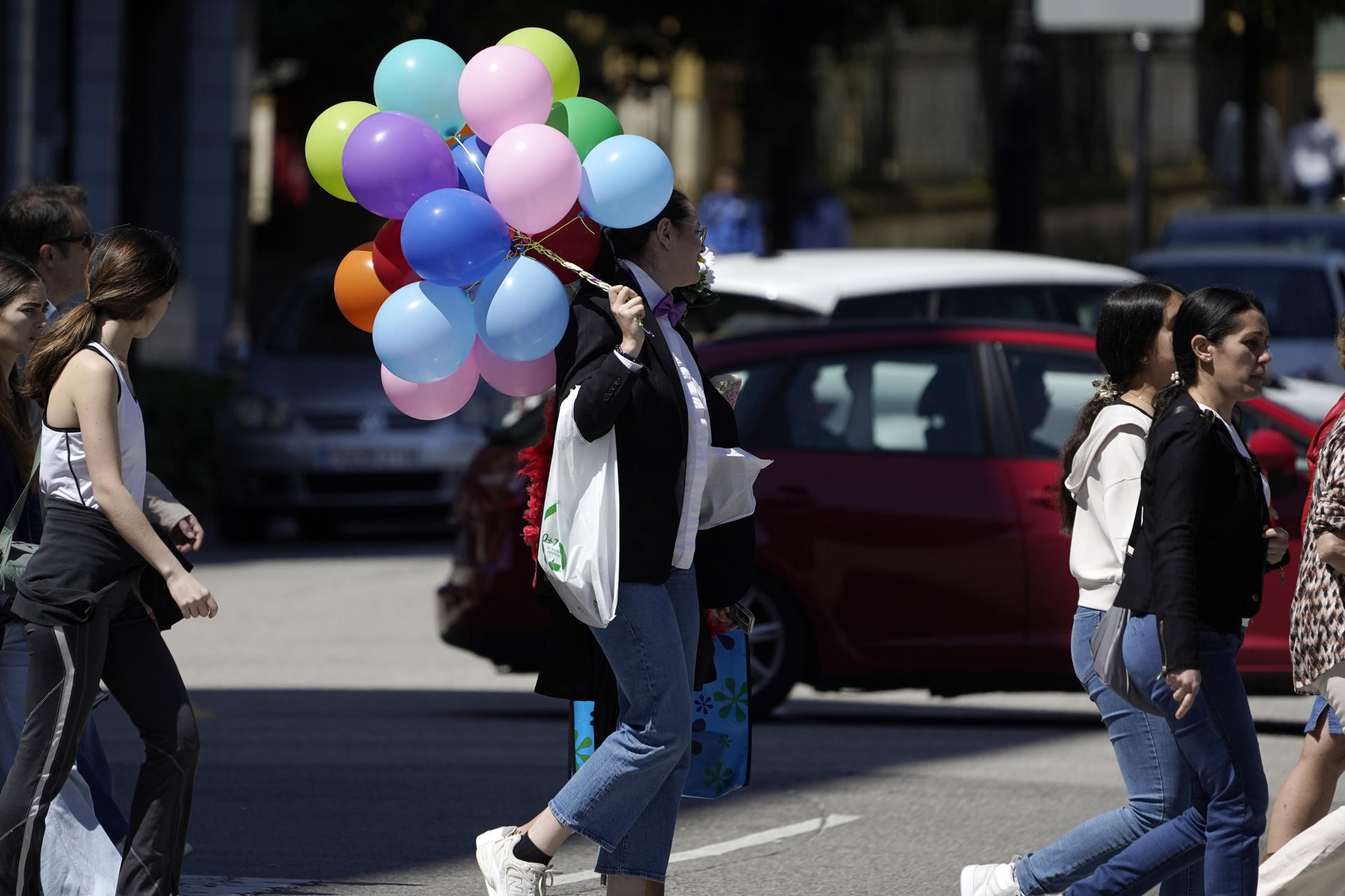 Imagen de una chica con globos en una céntrica calle de Oviedo en una soleada mañana, este sábado. EFE/Paco Paredes