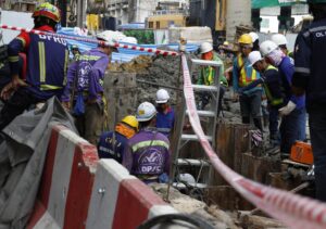 Rescatistas y obreros participan en una operación para rescatar a un trabajador que cayó en un socavón de 19 metros de profundidad en una obra de metro en Bangkok. EFE/EPA/NARONG SANGNAK