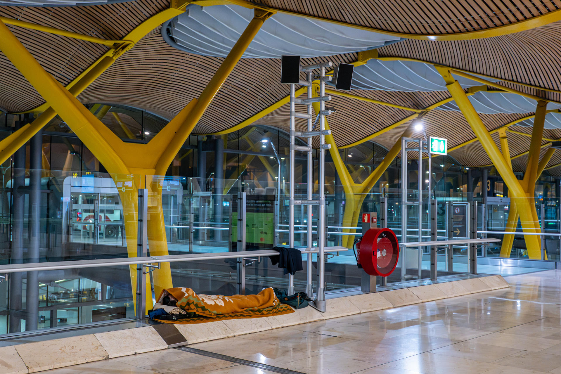 Una persona duerme en el Aeropuerto de Barajas. EFE/Fernando Villar