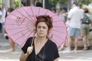 Una mujer se cubre del sol con una sombrilla en una calle del centro de Sevilla. EFE/José Manuel Vidal