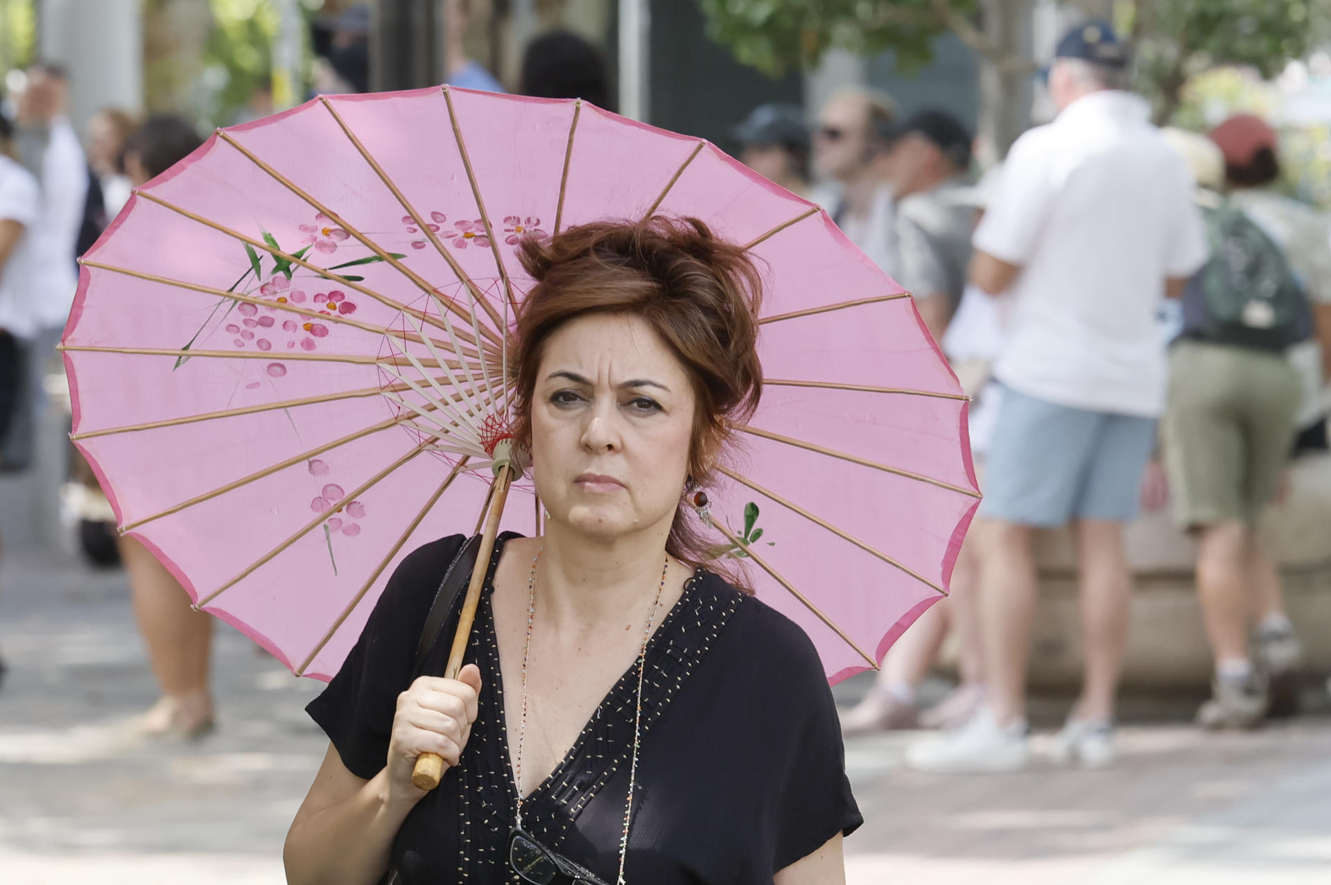 Una mujer se cubre del sol con una sombrilla en una calle del centro de Sevilla. EFE/José Manuel Vidal