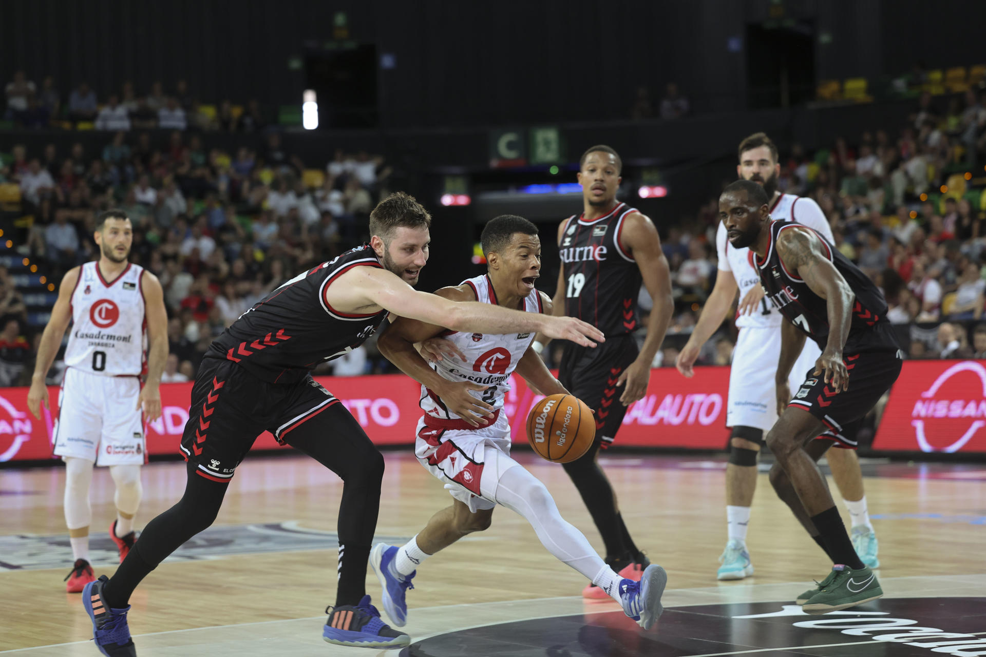 El base del Casademont Trae Bell-Haynes (c) entra a canasta ante el base del Bilbao Kristian Kullamae (i) durante el encuentro de la Liga Endesa entre Bilbao Basket y Casademont Zaragoza que se disputó en el Bilbao Arena. EFE/ Luis Tejido
