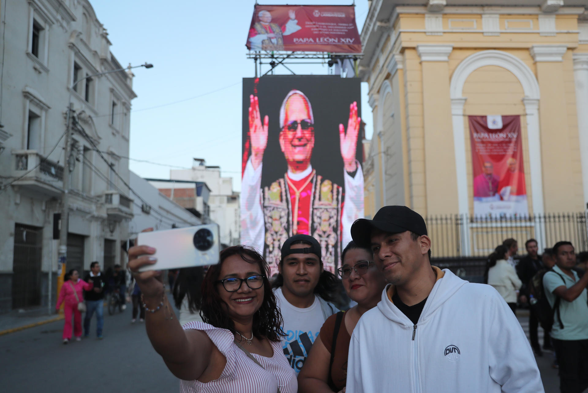 Personas toman una fotografía con la imagen del papa León XIV de fondo en la plaza central de Chiclayo (Perú). EFE/Paolo Aguilar
