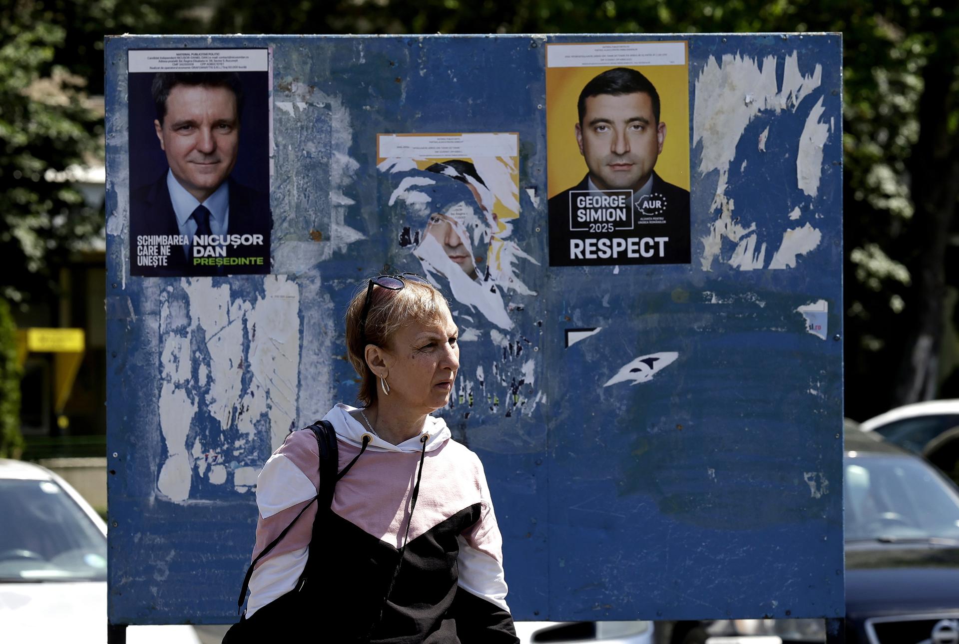 Una mujer rumana pasa por una valla publicitaria que muestra carteles electorales de los candidatos para la segunda vuelta de las elecciones presidenciales, en Bucarest, Rumanía, el 15 de mayo de 2025. EFE/EPA/ROBERT GHEMENT