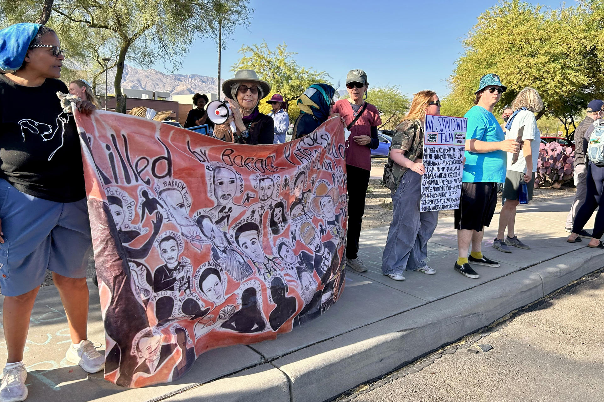 Personas sostienen carteles y banderas durante una manifestación este viernes, en Tucson (Estados Unidos). EFE/ María León