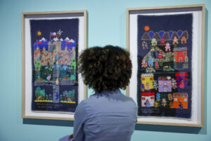Una colección de arpilleras, tapices tejidos por mujeres familiares de detenidos o desaparecidos para dar testimonio de la violencia durante la dictadura de Pinochet, se exhiben desde este jueves en el Palau Robert de Barcelona en una exposición que reivindica el papel de la memoria en la consolidación de la democracia. En la imagen una joven observa las obras 'El golpe' (i) y 'Secuestro y muerte de José Carrasco' (d). EFE/Toni Albir