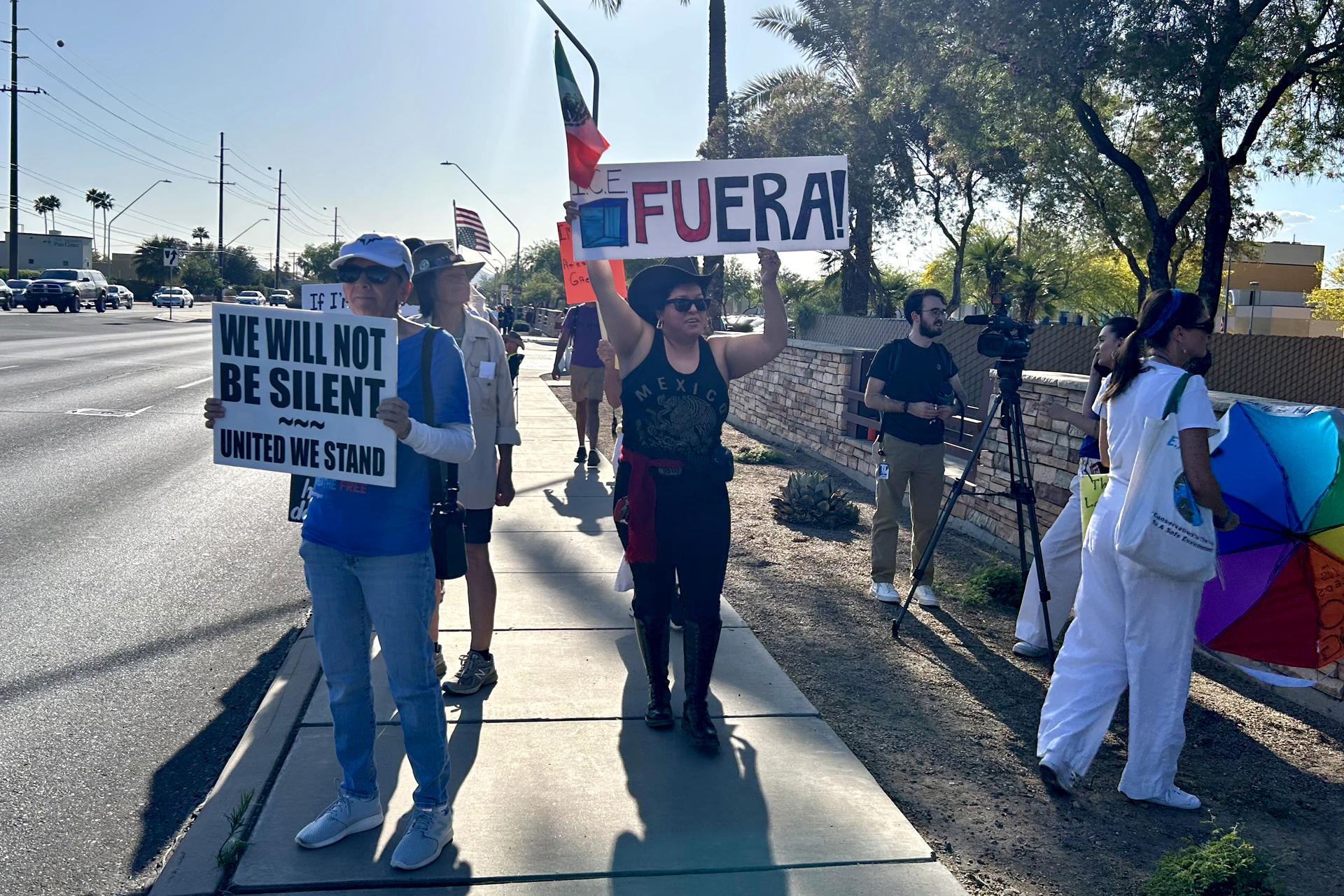 Personas sostienen carteles y banderas durante una manifestación este sábado, en Tucson (Estados Unidos). EFE/ María León