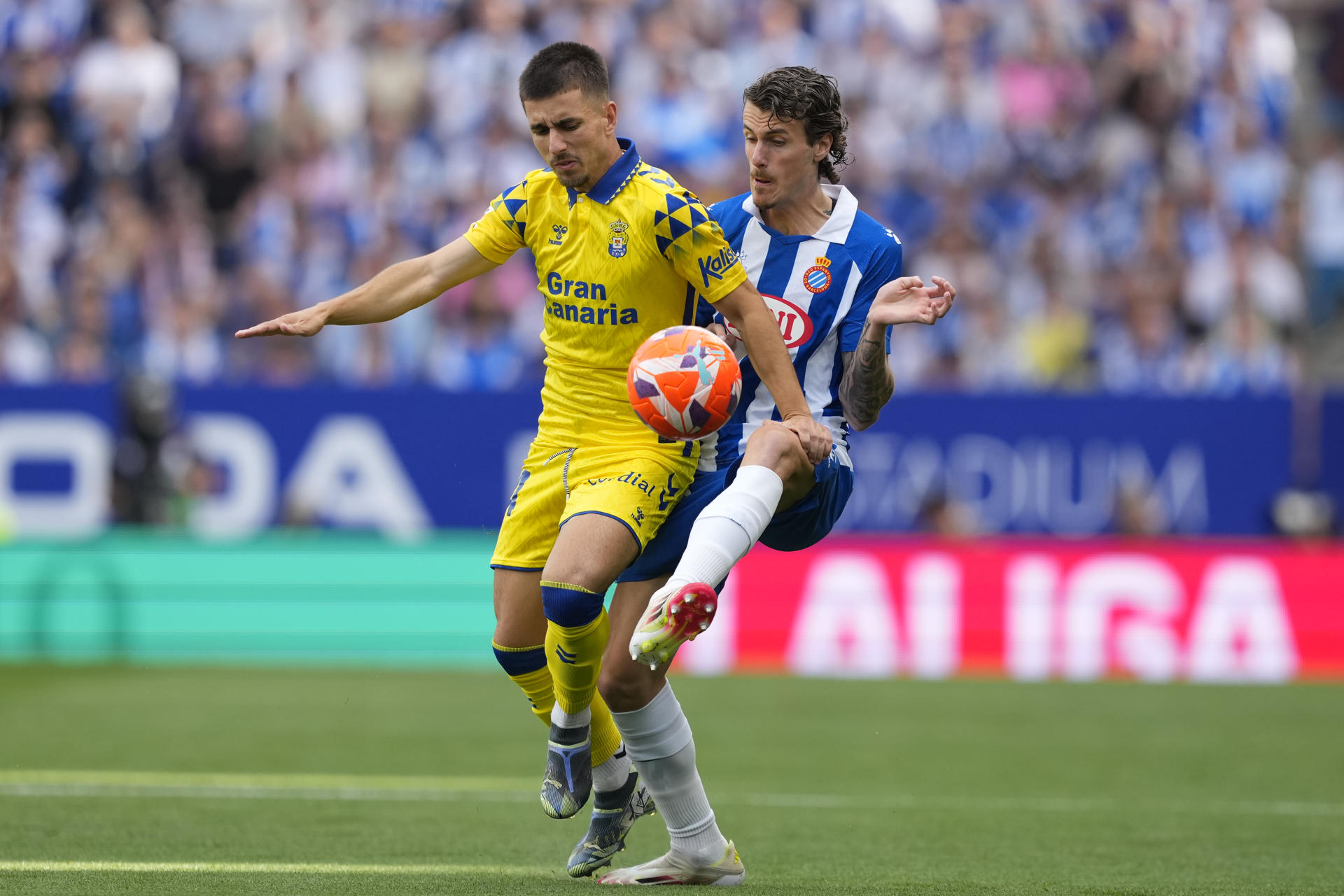 El defensa del Espanyol Carlos Romero (d) pelea un balón con Manuel Fuster, de Las Palmas, durante el partido de LaLiga de fútbol que RCD Espanyol y UD Las Palmas disputan este sábado en el RCDE Stadium. en Barcelona. EFE/Alejandro García