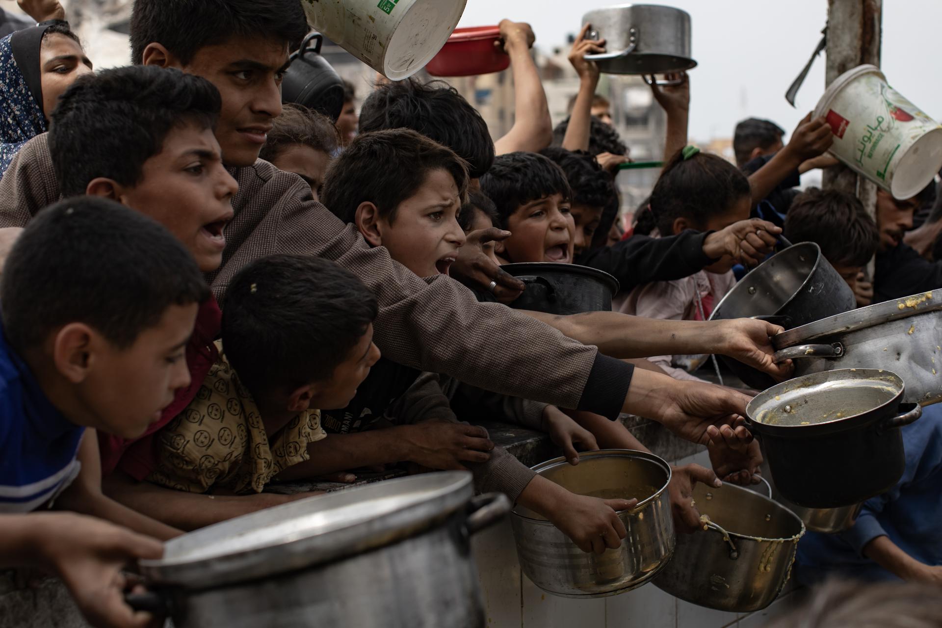 Fotografía de archivo que muestra a palestinos desplazados internos haciendo fila para recibir una ración de comida de un comedor social en Jabalia, al norte de la Franja de Gaza. EFE/EPA/HAITHAM IMAD