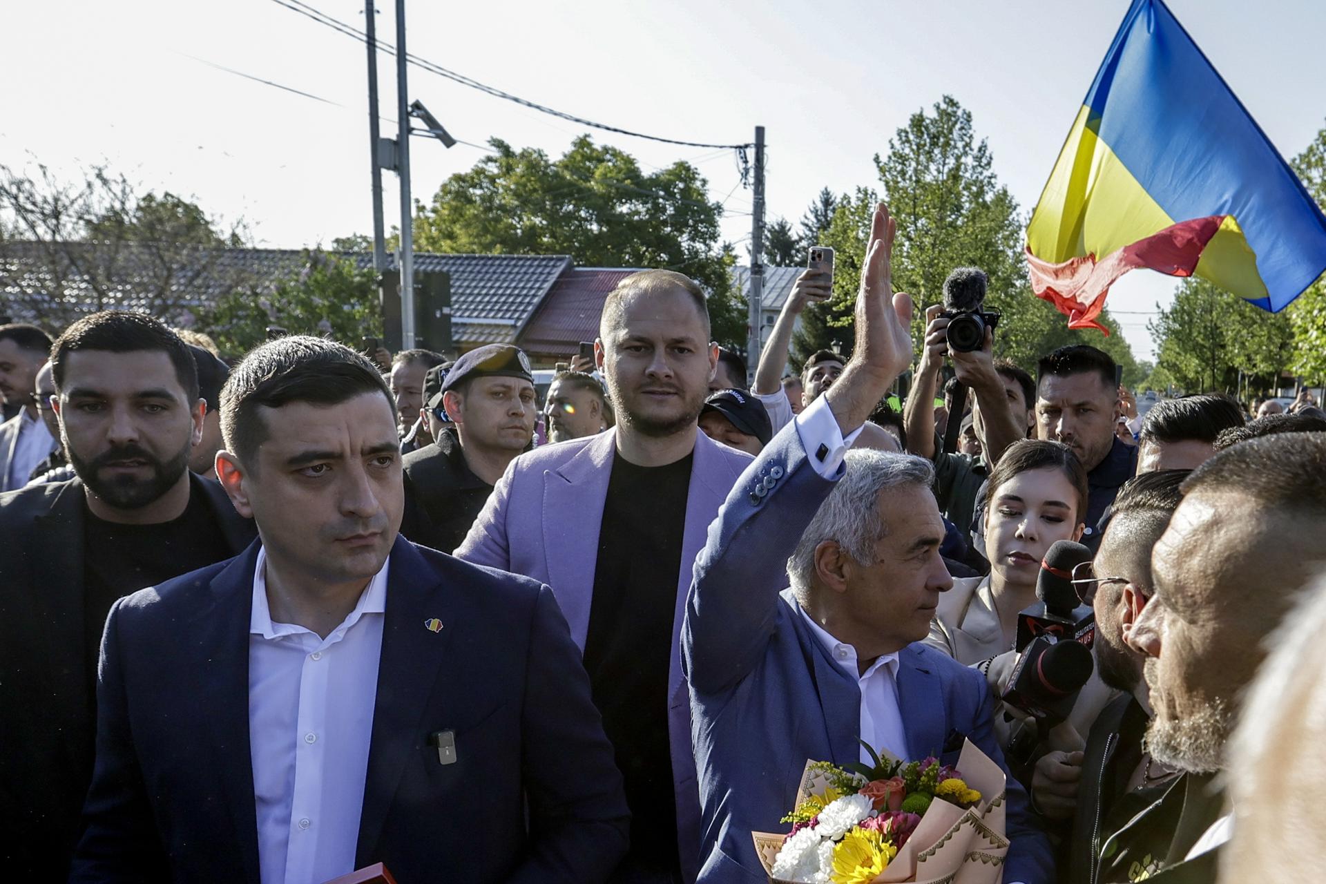 El candidato presidencial vetado Calin Georgescu saluda a sus seguidores mientras camina con el líder del partido de extrema derecha Alianza para la Unión de los Rumanos (AUR) George Simion (2-L) después de emitir sus votos en la primera vuelta de las elecciones presidenciales en la localidad de Mogosoaia, cerca de Bucarest, Rumanía, el 04 de mayo de 2025. Los votantes rumanos regresan a las urnas este fin de semana para repetir la primera vuelta de las elecciones presidenciales, celebrada originalmente el 24 de noviembre de 2024 y posteriormente anulada, con alrededor de 18 millones de ciudadanos con derecho a voto, según la Autoridad Electoral Permanente (AEP). (Elecciones, Rumanía, Bucarest) 
EFE/EPA/ROBERT GHEMENT
//////////
Mogosoaia (Romania), 04/05/2025.- Banned presidential candidate Calin Georgescu waves to supporters as he walks with leader of far-right party Alliance for the Union of Romanians (AUR) George Simion (2-L) after casting their ballots in the first round of presidential elections in Mogosoaia village, near Bucharest, Romania, 04 May 2025. Romanian voters are returning to the polls this weekend for a repeat of the first round of the presidential election, originally held on 24 November 2024 and later annulled, with around 18 million citizens eligible to vote, according to the Permanent Electoral Authority (AEP). (Elecciones, Rumanía, Bucarest) EFE/EPA/ROBERT GHEMENT
